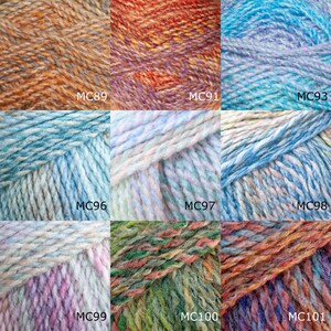 Op de afbeelding: Een verzameling garenklossen in verschillende kleurcombinaties, waaronder oranje, blauw, groen en paars. Elke klos is gemarkeerd met een code, zoals MC89, MC91, MC93, MC96, MC97, MC98, MC99, MC100 en MC101.