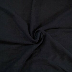 May include: A close-up of a black fabric with a soft, smooth texture. The fabric is folded and draped, creating a sense of depth and dimension.