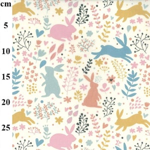 May include: A white fabric with a repeating pattern of pink, blue, and yellow bunnies hopping through a field of flowers and hearts.