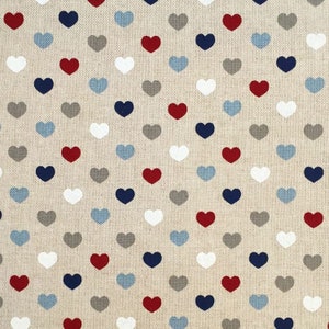 May include: A beige fabric with a repeating pattern of small hearts in red, white, blue, gray, and light blue.