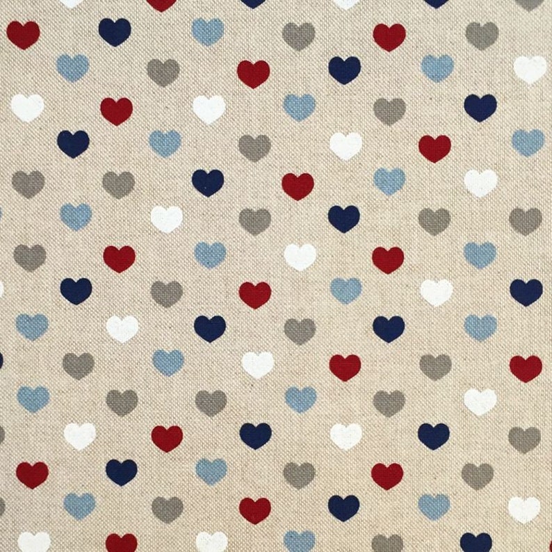 May include: A beige fabric with a repeating pattern of small hearts in red, white, blue, gray, and light blue.
