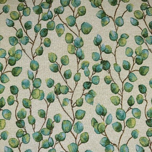 May include: A cream-coloured fabric with a repeating pattern of green and blue leaves. The leaves are arranged in a flowing, organic pattern, creating a natural and calming aesthetic.