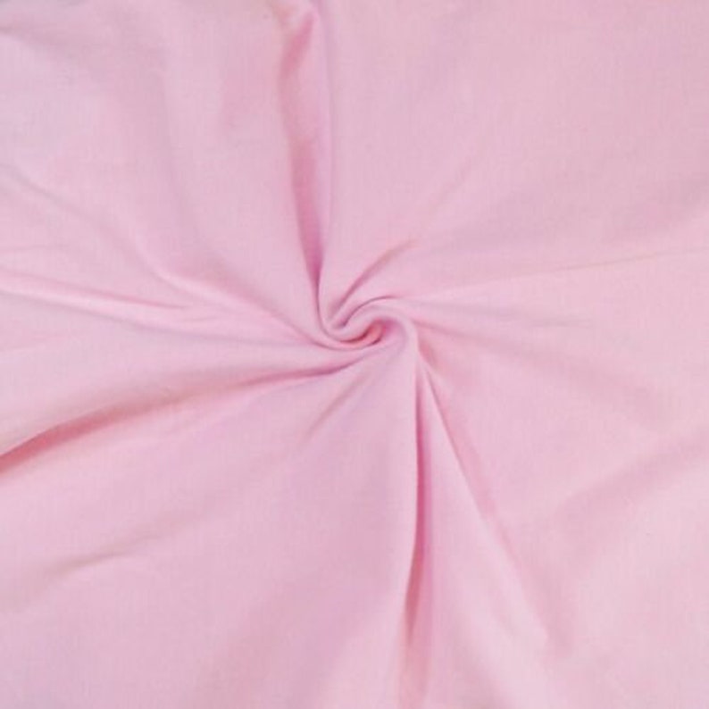 May include: A close-up of a soft, pink fabric with a smooth texture. The fabric is folded and draped, creating a gentle curve.