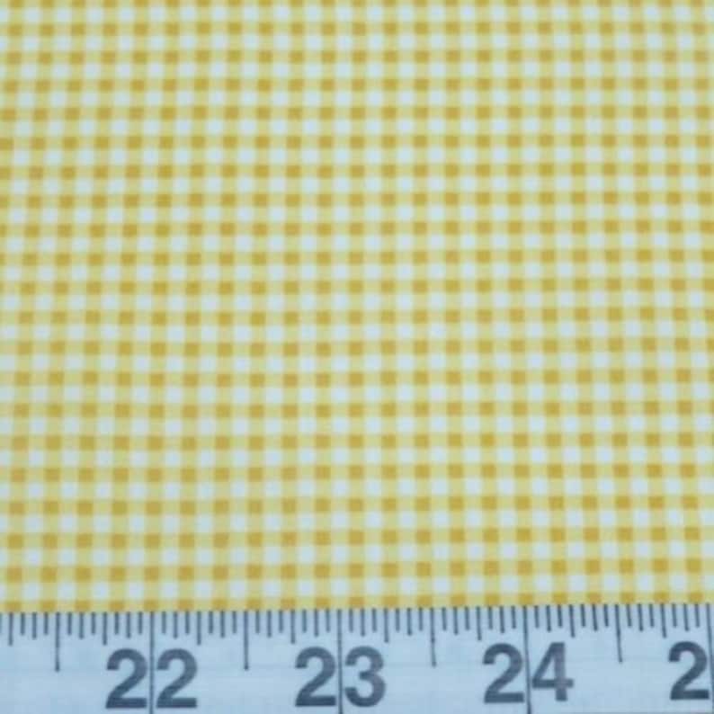 K&ouml;nnte beinhalten: Gelber und wei&szlig;er Gingham-Stoff mit einem Lineal, das 22 bis 25 Zoll anzeigt.