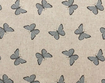May include: A beige fabric with a repeating pattern of blue butterflies. The butterflies are stylized and have a simple design.