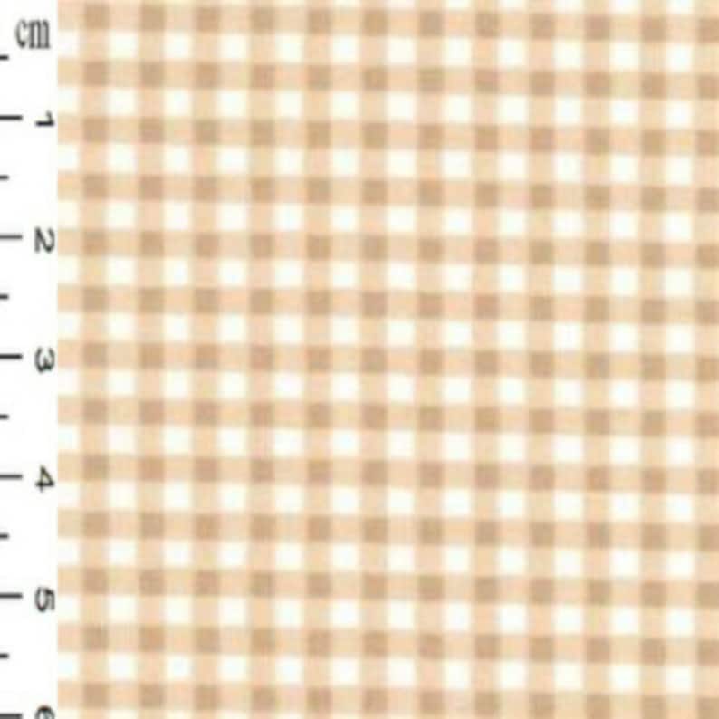 K&ouml;nnte beinhalten: Beige und wei&szlig;er Gingham-Stoff mit einem kleinen Karomuster. Der Stoff wird gegen ein wei&szlig;es Lineal mit Markierungen in Zentimetern gezeigt.