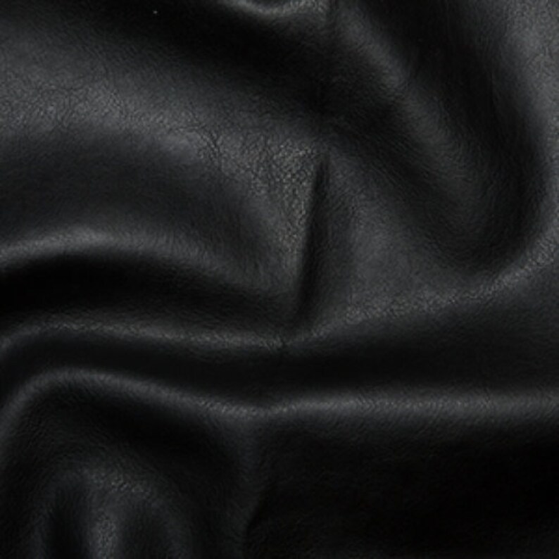 May include: Black faux leather fabric with a textured surface. The fabric is wrinkled and folded.