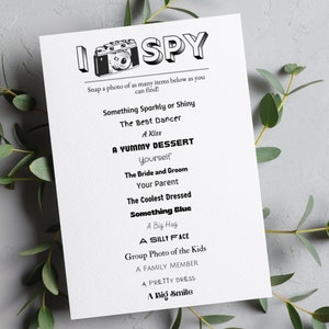 May include: A printable I Spy game with a camera graphic and a list of items to find, including "Something Sparkly or Shiny", "The Best Dancer", "A Kiss", "A Yummy Dessert", "Yourself", "The Bride and Groom", "Your Parent", "The Coolest Dressed", "Something Blue", "A Big Hug", "A Silly Face", "Group Photo of the Kids", "A Family Member", "A Pretty Dress", and "A Big Smile".