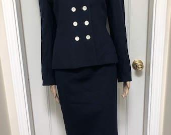 May include: A navy blue skirt suit with a double-breasted jacket and a wide collar. The jacket has white buttons.