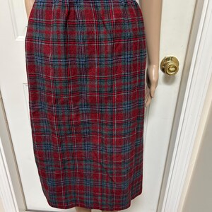May include: A knee-length skirt with a red, green, and blue plaid pattern. The skirt has a fitted waistband and a straight silhouette. The fabric appears to be a woven material, suitable for cooler weather.