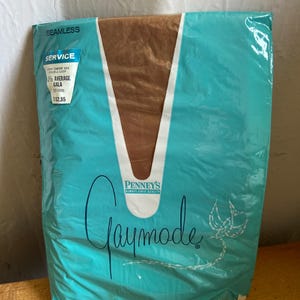 May include: A package of vintage hosiery in a teal and brown color scheme. The package features the brand name "Gaymode" in cursive script, along with the "Penney's" logo. The package also includes text indicating the hosiery is seamless.