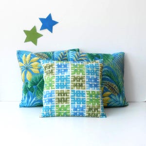May include: Three decorative throw pillows with a tropical theme. The pillows are blue, green, and yellow with a geometric pattern.