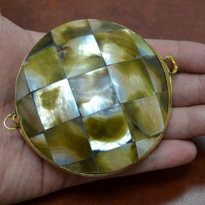 May include: A round, gold-toned pendant with a checkered pattern made of iridescent mother-of-pearl tiles.