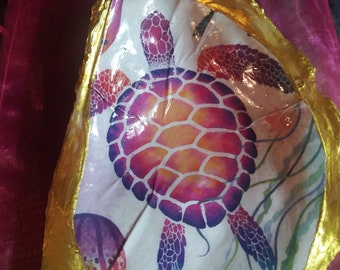 May include: A white seashell with a gold rim, painted with a colourful sea turtle and coral reef design.