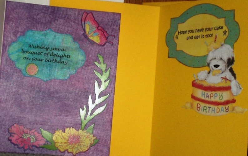 Może przedstawiać: Fioletowa kartka z niebiesko-białym wzorem kwiatowym i tekstem "Wishing you a bouquet of delights on your birthday". Kartka jest otwarta, aby ujawnić ż&oacute;łtą kartkę z zielono-białą ramką i tekstem "Hope you have your cake and eat it too!" oraz kresk&oacute;wkowym psem trzymającym tort z napisem "Happy Birthday".