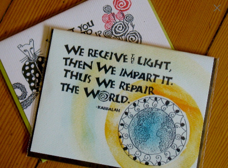 May include: A green card with a yellow and orange watercolor background. The card features a black and white illustration of a globe with a quote that reads "We receive the light, then we impart it. Thus we repair the world. -Kabbalah"