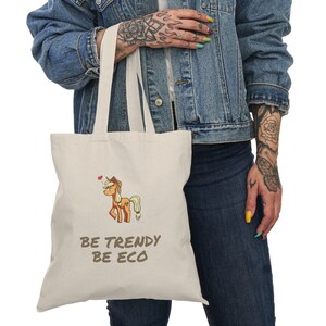 Peut inclure: Un sac fourre-tout beige avec un cheval de dessin animé et le texte "Be Trendy Be Eco".