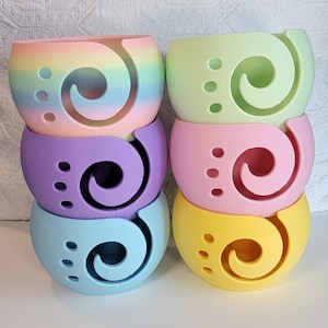 May include: Set of six colorful yarn bowls, each with a different pastel color and a swirl design. The bowls are stacked in a pyramid shape.