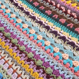 Puede incluir: Una manta de ganchillo colorida con una variedad de puntos y colores, incluyendo verde, azul, amarillo, rosa y morado.