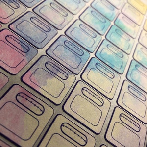 May include: A sheet of colorful, watercolor-painted stickers with a stitched rectangle design. The stickers are arranged in a diagonal pattern.