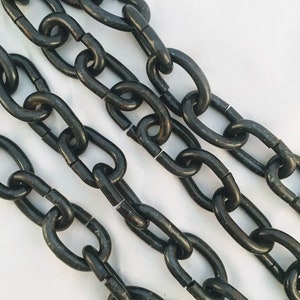Puede incluir: Tres cadenas de metal negro sobre una superficie blanca. Las cadenas est&aacute;n unidas entre s&iacute; y est&aacute;n hechas de metal grueso y duradero.