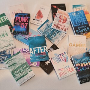 May include: A collection of paperback books with various titles and authors. The books are stacked and scattered on a white surface. Some of the titles include "After We Fell", "Punk 57", "Ugly Love", "Confess", "Birthday Girl", and "Before I Fall".