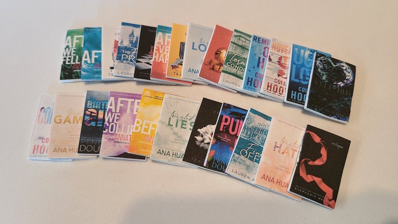 May include: A collection of paperback books with various titles and authors. The books are arranged in two rows on a white surface. The books have colorful covers with different designs and text. Some of the titles include "After We Fell", "After We Collided", "Twisted Lies", "The Prison", "The Love Hypothesis", "Ugly Love", and "The Selection".