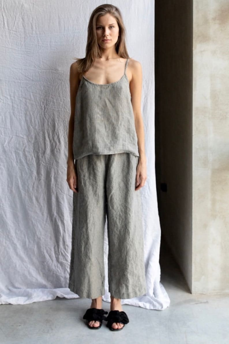 May include: A two-piece set consisting of a sleeveless camisole top with thin shoulder straps and wide-leg trousers. Both garments are made from a grey and white pinstriped fabric with a textured appearance, featuring a loose and relaxed fit.