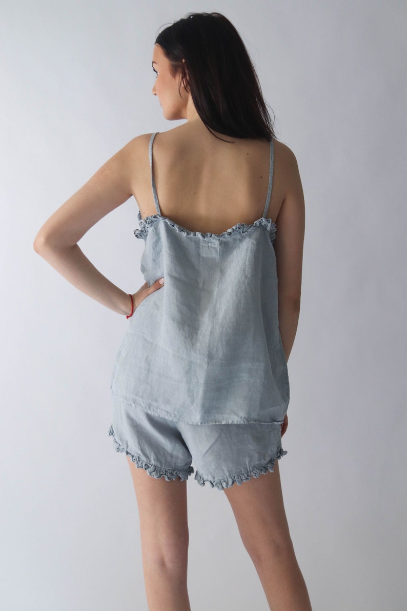 Puede incluir: Un conjunto de pijama de lino azul claro con una parte superior y pantalones cortos con volantes.