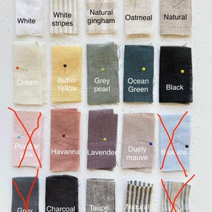 May include: A collection of fabric swatches in various colors and patterns, including white, cream, and black. The swatches are labeled with color names like "Butter Yellow" and "Ocean Green". Each swatch is pinned with a colored pin.