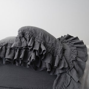 May include: A gray linen pillow with a ruffled edge. The pillow is made of a soft, comfortable fabric and has a relaxed, casual look.