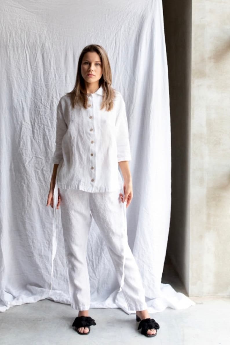May include: A white linen shirt and pants set with a button-up front and long sleeves. The shirt has a collar and the pants have a relaxed fit.