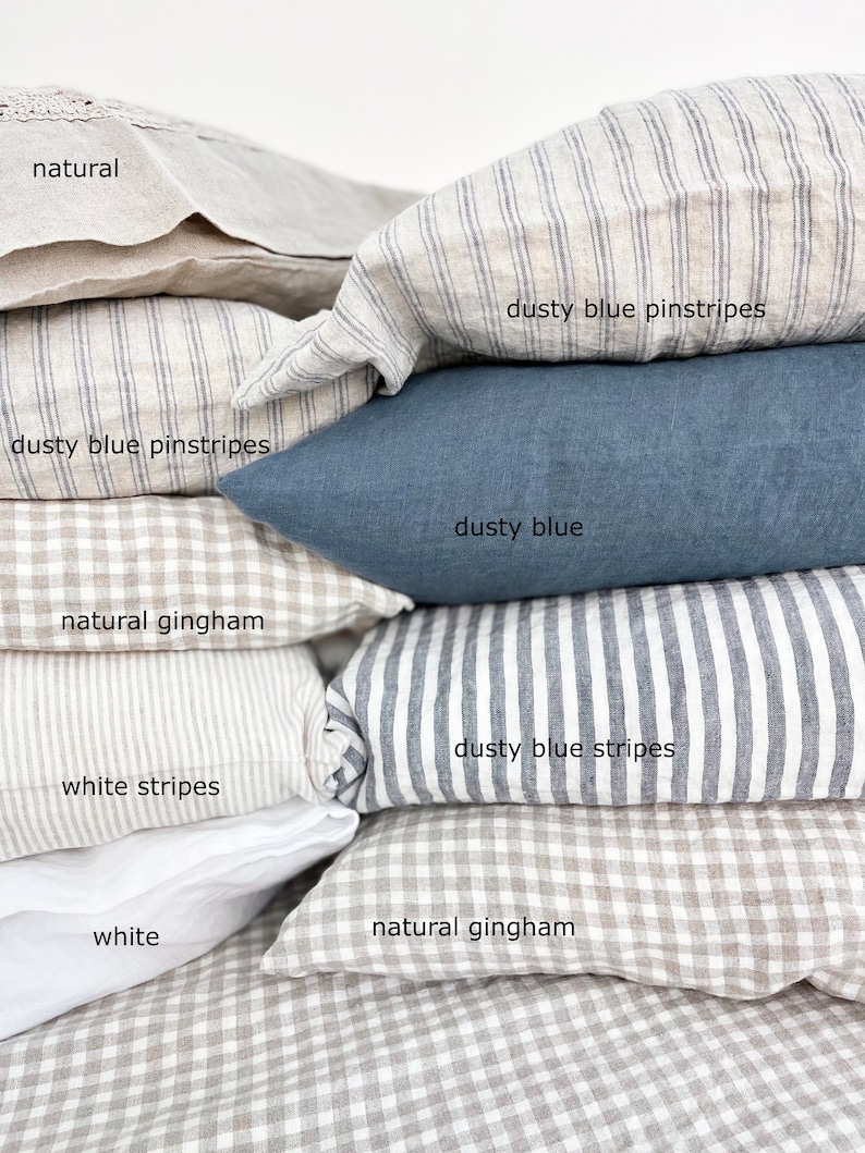 May include: A stack of various linen pillowcases in neutral tones and patterns. The selection includes natural, white, and dusty blue options. Patterns include pinstripes, stripes, and gingham. The text labels each pillowcase with its color or pattern.