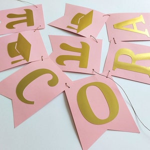 Pink and gold graduation banner with golden cap and maths  symbol Pi.