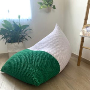 May include: A green and white knitted beanbag chair. The chair is shaped like a teardrop and has a white top and a green bottom.