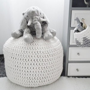 round crochet white pouf in kids room with a plush elephant on it.