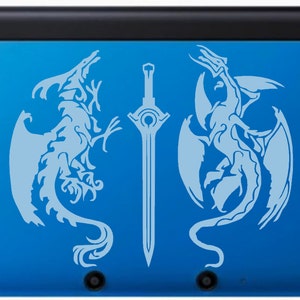 May include: A blue handheld gaming console featuring a light blue design of two dragons flanking a sword. The console has a black top and a glossy finish. The design is symmetrical and detailed.