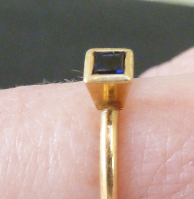 May include: A gold ring with a square-shaped blue gemstone set in a gold setting.