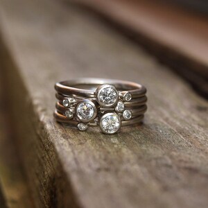 May include: A set of five silver rings with small round diamonds. The rings are stacked on top of each other, creating a unique and stylish look.