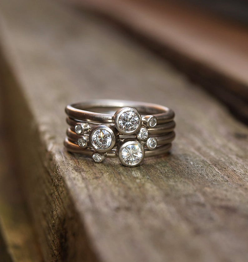 May include: A set of five silver rings with small round diamonds. The rings are stacked on top of each other, creating a unique and stylish look.