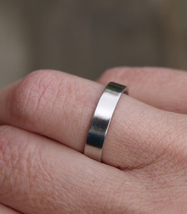 May include: A simple silver band ring worn on a finger.