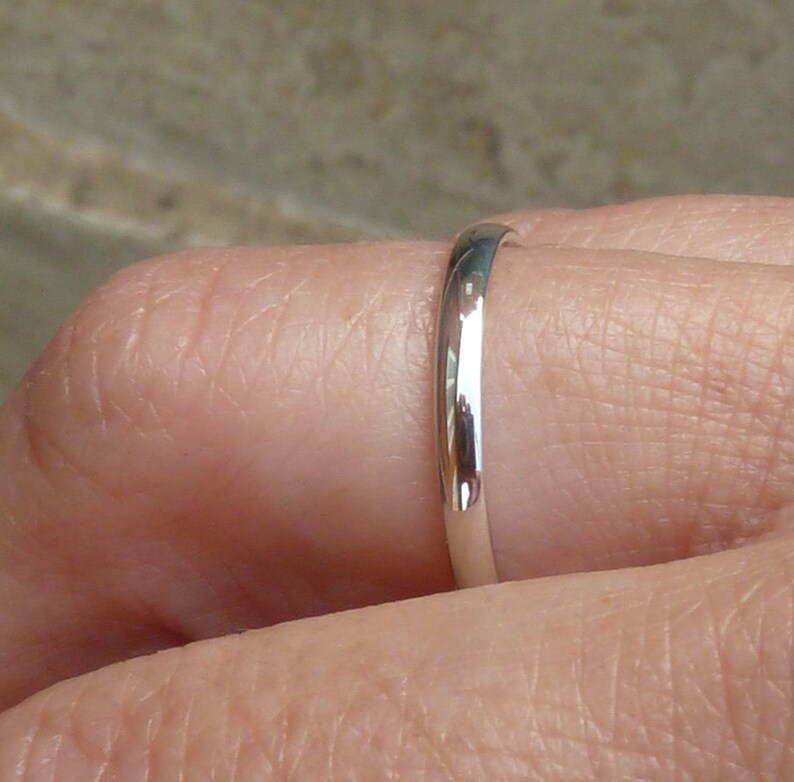 Puede incluir: Primer plano de un anillo de banda de plata usado en un dedo.