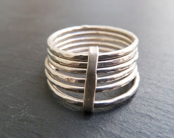 May include: Silver ring with a hammered finish and a stacked band design. The ring is made of multiple bands that are stacked on top of each other.