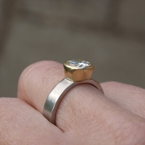 May include: A gold and silver ring with a large, clear, cushion-cut gemstone.