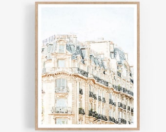 Könnte beinhalten: Ein Aquarellbild eines Pariser Gebäudes mit einer hellbeigen Fassade und einem grauen Dach. Das Gebäude hat viele Fenster und Balkone. Das Bild ist in einem hellen Holzrahmen gerahmt.