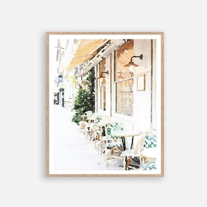 May include: Watercolor painting of a cafe with a white building and green chairs and tables on the sidewalk. The cafe has a awning and a sign in the window.
