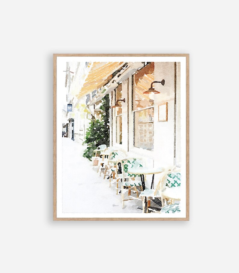 May include: Watercolor painting of a cafe with a white building and green chairs and tables on the sidewalk. The cafe has a awning and a sign in the window.