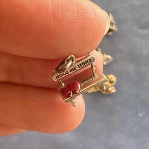 Peut inclure: Charme en argent avec deux c&oelig;urs rouges sur une petite table avec l'inscription "Hold Me Tight" grav&eacute;e sur le c&ocirc;t&eacute;.