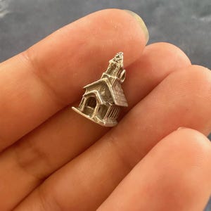 Peut inclure: Un charme en argent en forme d'&eacute;glise avec un clocher. Le charme est d&eacute;taill&eacute; avec des fen&ecirc;tres et une porte.