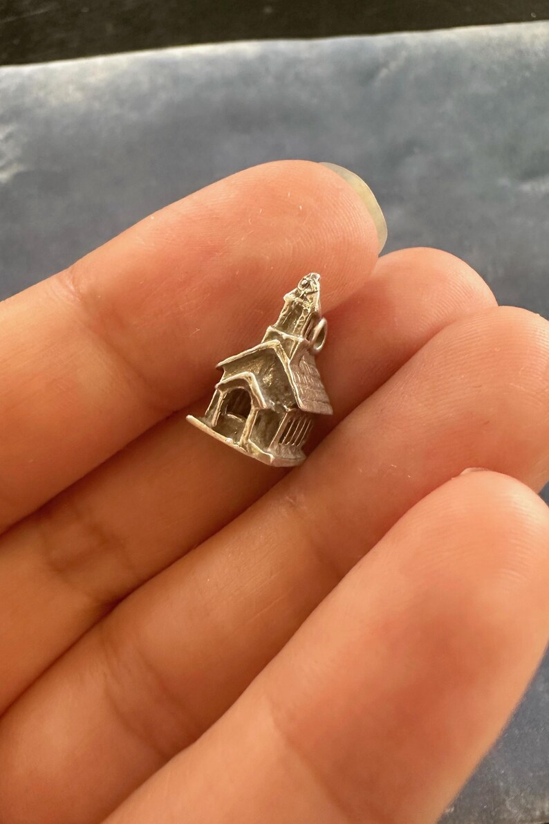 Peut inclure: Un charme en argent en forme d'&eacute;glise avec un clocher. Le charme est d&eacute;taill&eacute; avec des fen&ecirc;tres et une porte.